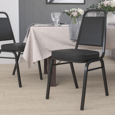 Hercules Series Trapezoidal Black Stacking banquet chair at a table